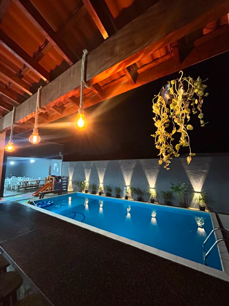 Piscina iluminada à noite no Espaço Canto dos Pássaros, chácara para eventos em Sorocaba